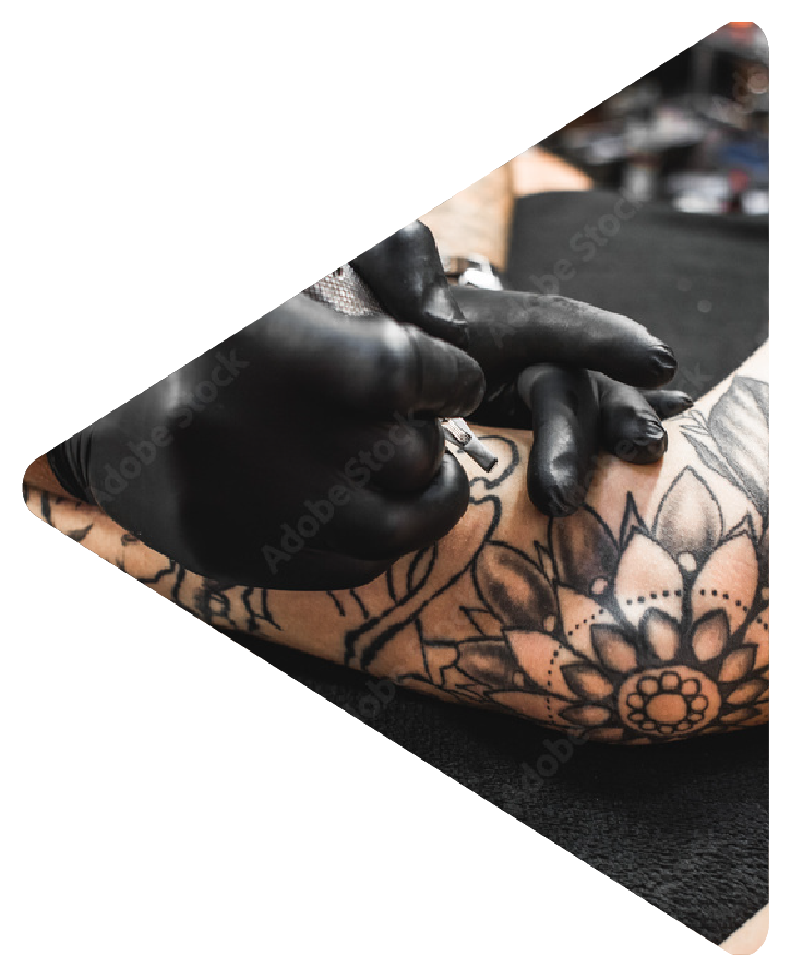 Tattoo artist with black gloves tattooing forearm of person with black ink